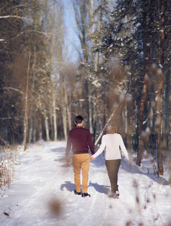 Young couple walking through the winter forest holding handsの写真素材