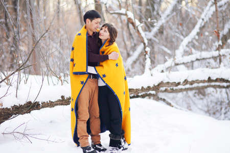 On a winter day, a young couple wrapped in a plaid spends time togetherの写真素材