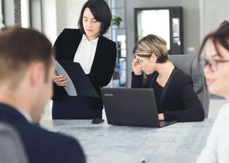 Two young business women in the office, working together on a project, discussing documentsの写真素材