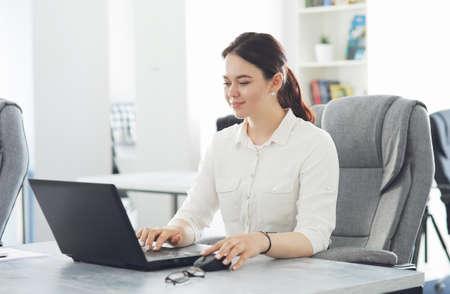 Young attractive business woman working in office smiling looking into laptopの写真素材