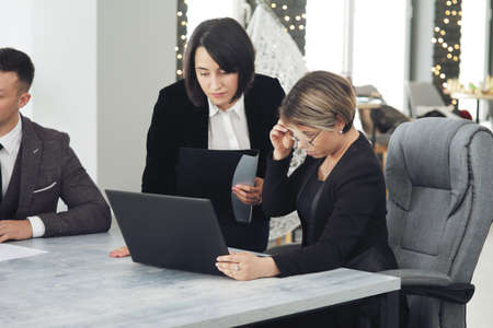 Two young business women in the office, analyzing information looking into a laptop.の写真素材