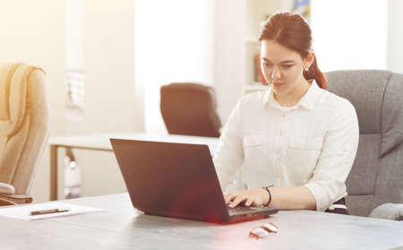 Young attractive business woman working in office smiling looking into laptop.の写真素材