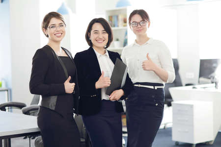 Three young successful business women in the office smiling happily.の写真素材