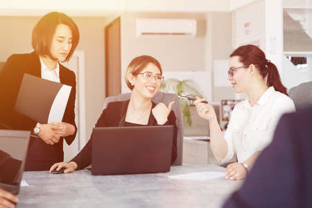 Three young successful business women in the office, together, happily working on a projectの写真素材