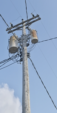 Wooden power utility pole with transformers and cables.