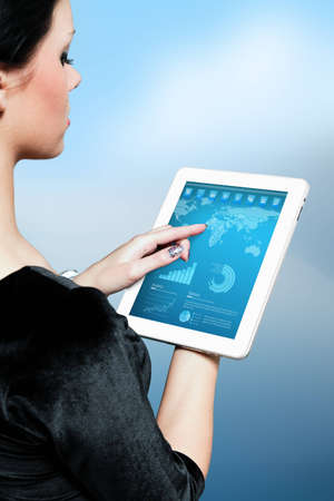 Cute brunette using interface of new touch pad device  Stylish modern icons, world map and infographics on the screen  Future lifestyle collection の写真素材