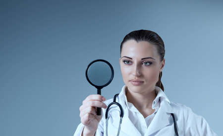 Young female doctor holding magnifying glass in right hand  Empty space to place your logo   text   product  Medical   pharmaceutical research concept  Healthcare collection の写真素材