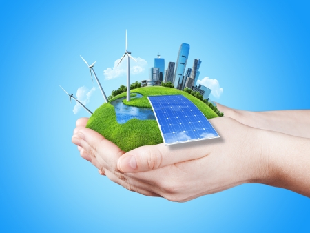 Hands holding clear green meadow with sun battery block, wind mill turbines and city skyscrapers  Concept for ecology, growing business, freshness, freedom and other lifestyle issues  Green fields collection の写真素材