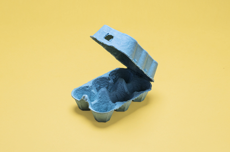 Empty and open half dozen egg carton container.  Opening six egg crate on a bright pastel yellow background with copy space and room for text on a bright pastel yellow backgroundの写真素材