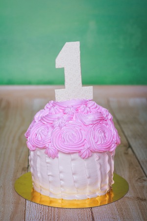 Pink cream birthday cake with number Oneの写真素材