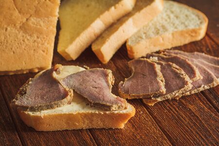 Bread with butter and slices of veal on wooden backgroundの写真素材