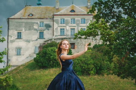 Beautiful young woman in blue dress standing back in dramatic poseの写真素材