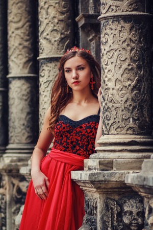 Beautiful young woman in red dress with corset and coronetの写真素材