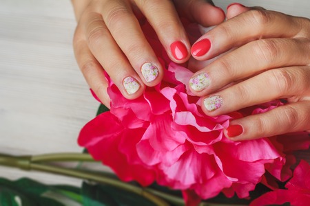 Red nail art with printed flowers on light wooden backgroundの写真素材