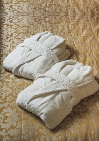 white bathrobe on the bed in the hotelの写真素材