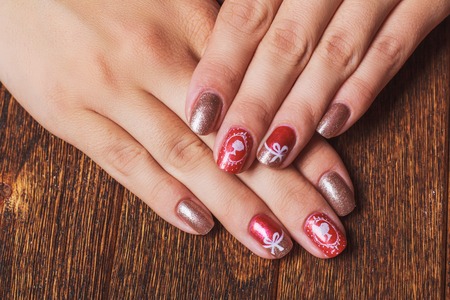 Festive nail art in pink and gold colors on dark wooden backgroundの写真素材