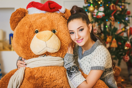 Beautiful young brunette girl with soft bear toys under New Year treeの写真素材
