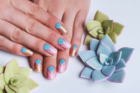 Nail art with bright gold, pink and  light blue chevron pattern on light backgroundの写真素材