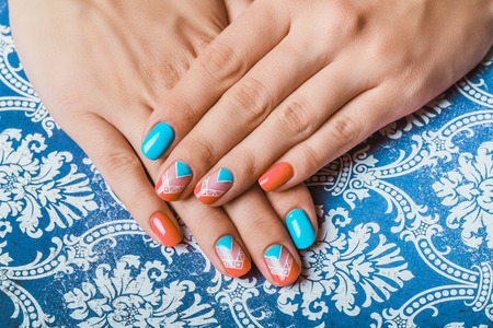 Nail art with bright orange and light blue chevron on pattern paper backgroundの写真素材