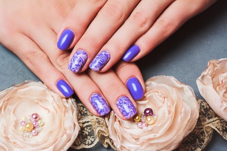 Purple nail art with pink floral pattern on grey stone backgroundの写真素材
