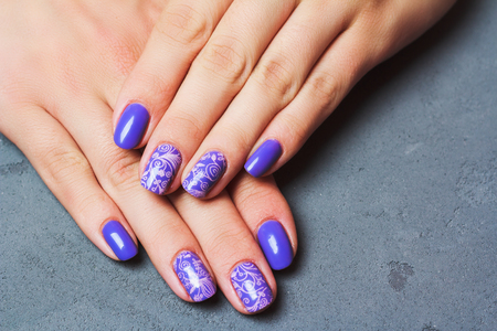 Purple nail art with pink floral pattern on grey stone backgroundの写真素材