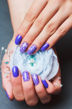 Purple nail art with pink floral pattern on grey stone backgroundの写真素材