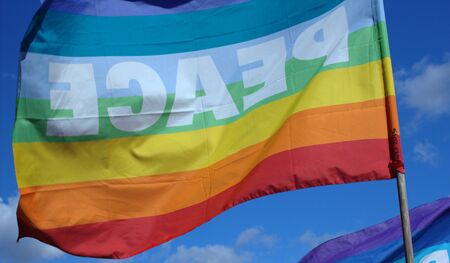 View of a floating peace flag from behind and under a blue skyの写真素材