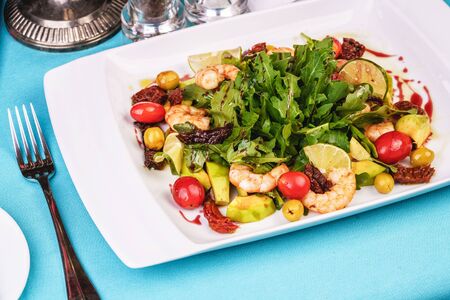 Grilled shrimps, cherry tomatoes, arugula, greens, avocado, lime and olives salad with balsamic dressingの写真素材