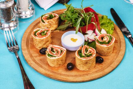 Mediterranean snack. Rolls with salmon, cucumber and vegetables with cream sauceの写真素材