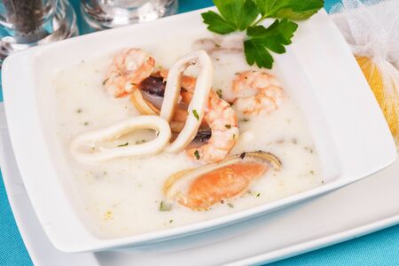 Creamy cheese soup with seafood and chicken on blue backgroundの写真素材