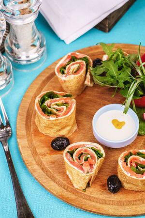 Mediterranean snack. Rolls with salmon and vegetables with cream sauceの写真素材