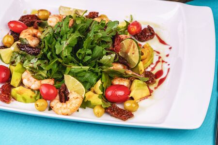 Grilled shrimps, cherry tomatoes, arugula, greens, avocado, lime and olives salad with balsamic dressingの写真素材