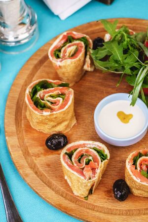 Mediterranean snack. Rolls with salmon and vegetables with cream sauceの写真素材