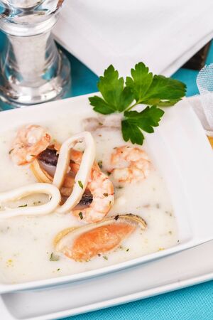 Creamy cheese soup with seafood and chicken on blue backgroundの写真素材