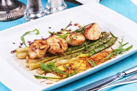 European recipe, Mediterranean dish. Caramelized asparagus with scallops, rose petals and arugulaの写真素材