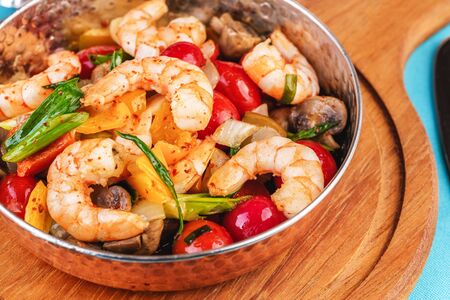 Seafood, Mediterranean cuisine, European dish. Warm salad of grilled fish pieces, shrimps and mussels in a frying pan, with grilled vegetables - with green onions, greens, mushrooms and vegetables.の写真素材