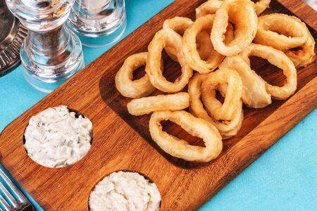 European cuisine, Mediterranean dish. Squid rings fried in batter snack for beer with cream sauce and steamed riceの写真素材