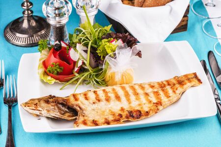 Mediterranean dish, European cuisine. Rainbow trout, grilled, served with vegetables - tomato, lettuce, radish, iceberg cabbageの写真素材