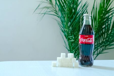 Kazakhstan Almaty, October 18, 2019. A bottle of Coca-Cola stands on a table with refined sugar...