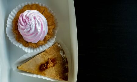 delicate dessert, a basket with light cream of light pink meringue and a nutty piece of cake on a...