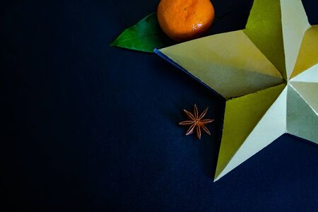 Dark textured christmas background with tangerines, citrus leaves, star anise, artificial star and cinnamon sticks. Background for banner, copyspace. view from above.の写真素材