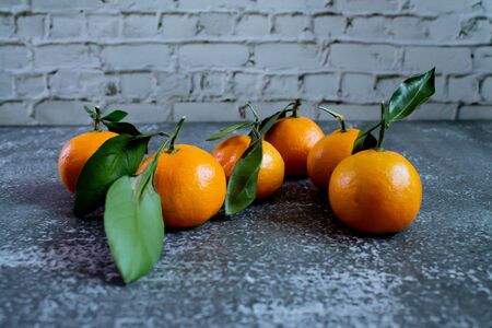 Gray concrete background with a brick wall, tangerines with leaves and twigs view from the top. New Year, in the style of health.の写真素材