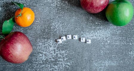 Gray background, oranges with leaves, red and greener apples from the top view from the top. The inscription fruits in Russian.の写真素材