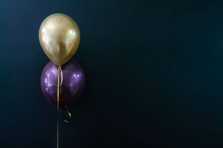 golden balloon and violet balloon on a dark background. Holiday Concept, Postcard, Copyspace.の写真素材