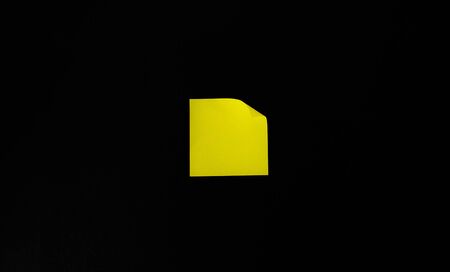 Yellow office sticker on a black wall.