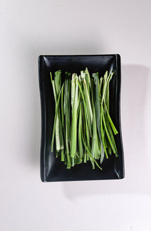 full green onion on a black plate. View from above. Chinese cuisine, ingredient for hotpotの写真素材