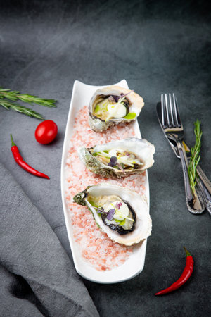 fresh oysters on red sea salt on a white plateの写真素材