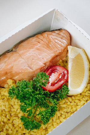 food in containers. proper nutrition, daily diet, weight loss. greens, tomato, lemon salmon steak with couscous side dish. Top viewの写真素材
