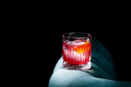 red cocktail with berry syrup and round ice with blackberries side view
