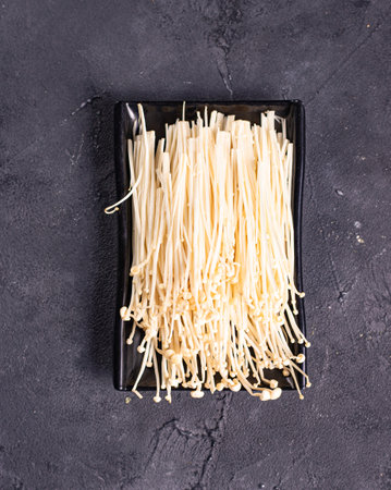 isolated enoki mushrooms called golden needle on a black plate.Chinese cuisine, hotpot ingredientの写真素材